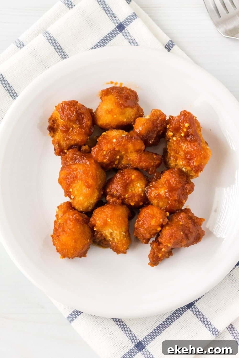 overhead view of a white plate with air fryer frozen cauliflower wings tossed in bbq sauce served on it