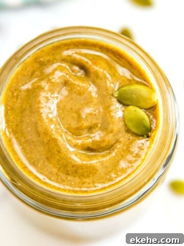 A jar of pumpkin seed butter garnished with a couple pumpkin seeds.