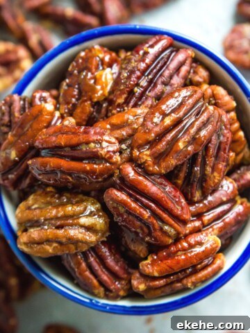 A bowl of honey glazed pecans, surrounded by more pecans.