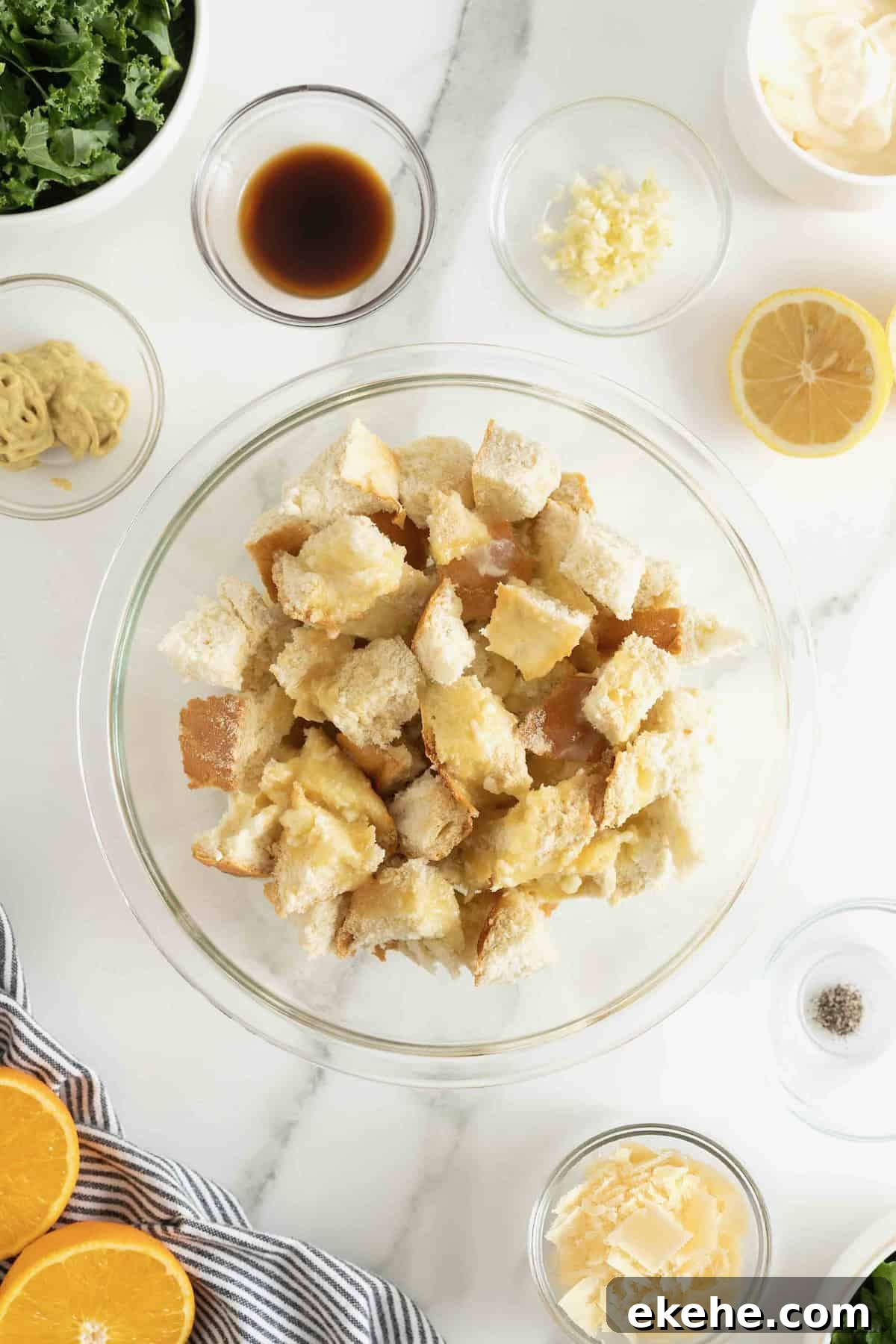 Cubed bread in a large glass mixing bowl tossed with spices.