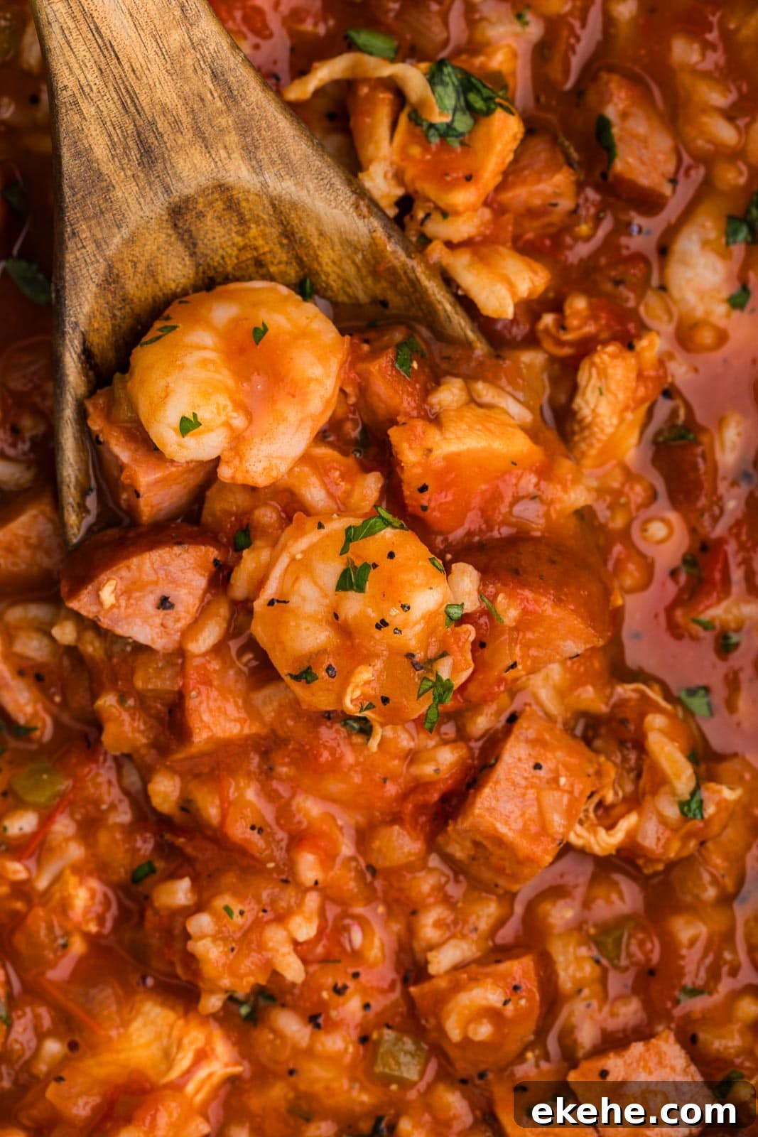closeup view of cooked jambalaya with wooden spoon inserted