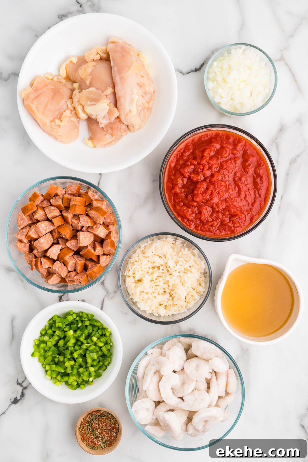 bowls of ingredients to include chicken breasts, diced Andouille sausage, diced green peppers, diced white onion, Creole seasoning, cooked white rice, chicken broth, crushed tomatoes and raw shrimp