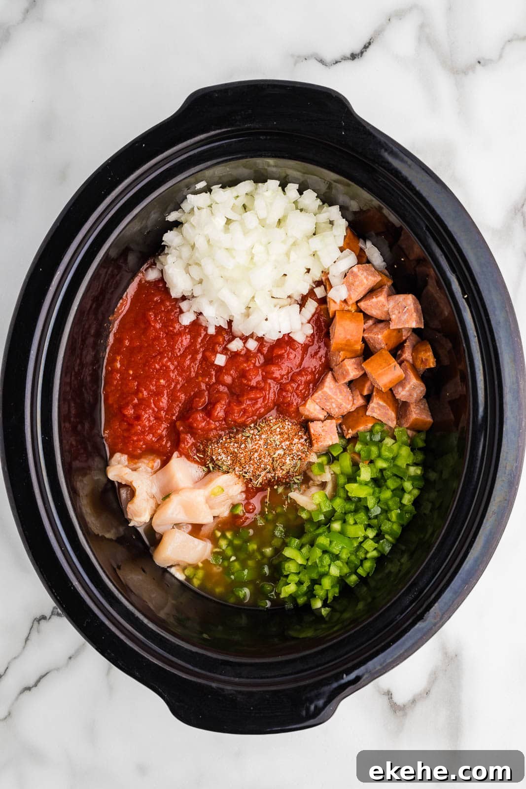 black slow cooker with all ingredients added except for shrimp and rice