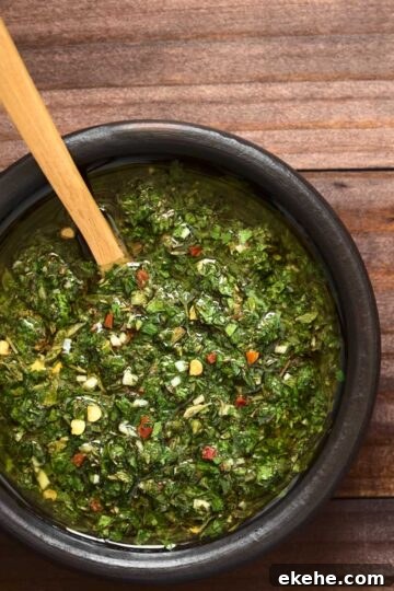 a black bowl of chimichurri sauce on a wood table