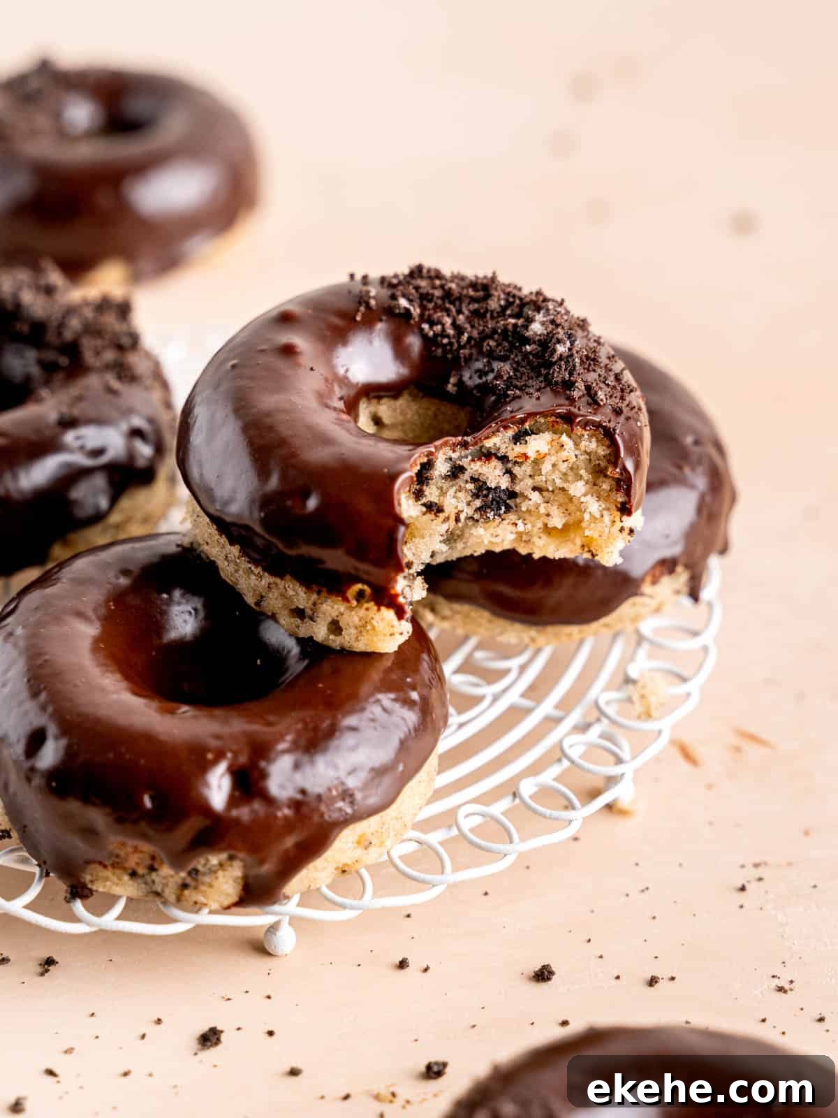 Cookies and cream donuts stacked on a wire cooling rack.