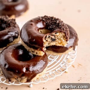 Cookies and cream donuts stacked on a wire cooling rack.