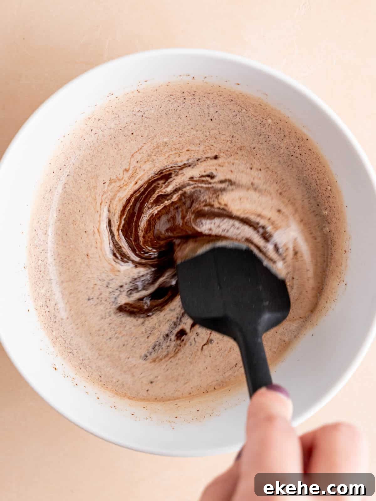 Stirring chocolate and hot cream to make chocolate ganache.