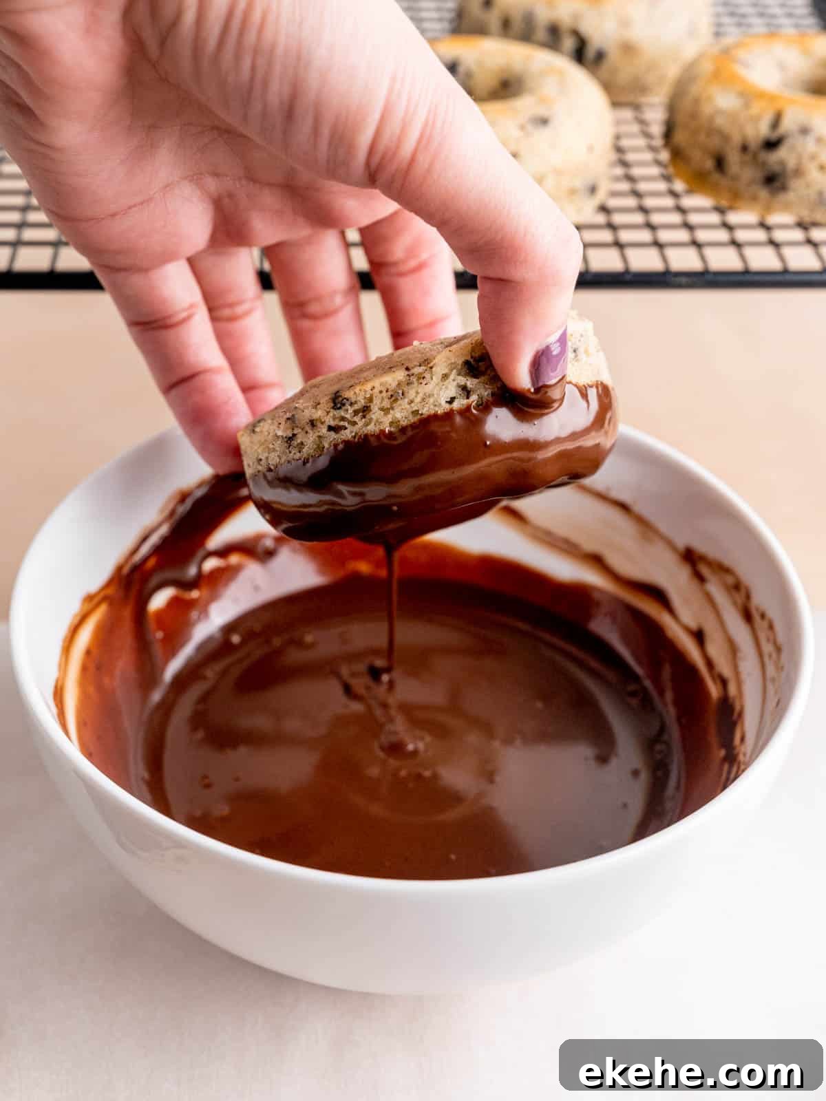 Dipping the top of a cookies and cream donut into chocolate ganache.