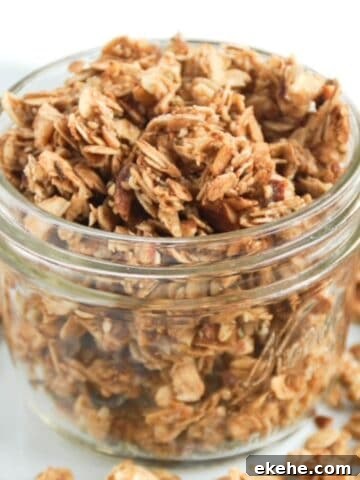 Chunky granola in a glass jar with granola around the base of the jar.