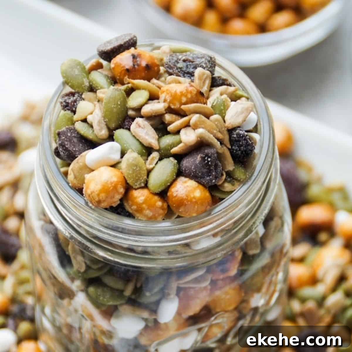 Up close image of nut free trail mix in a glass mason jar (top view). Trail mix also around the base of the glass jar.