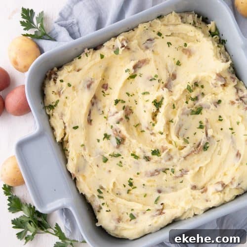 mashed potato casserole topped with parsley in a blue square casserole dish.