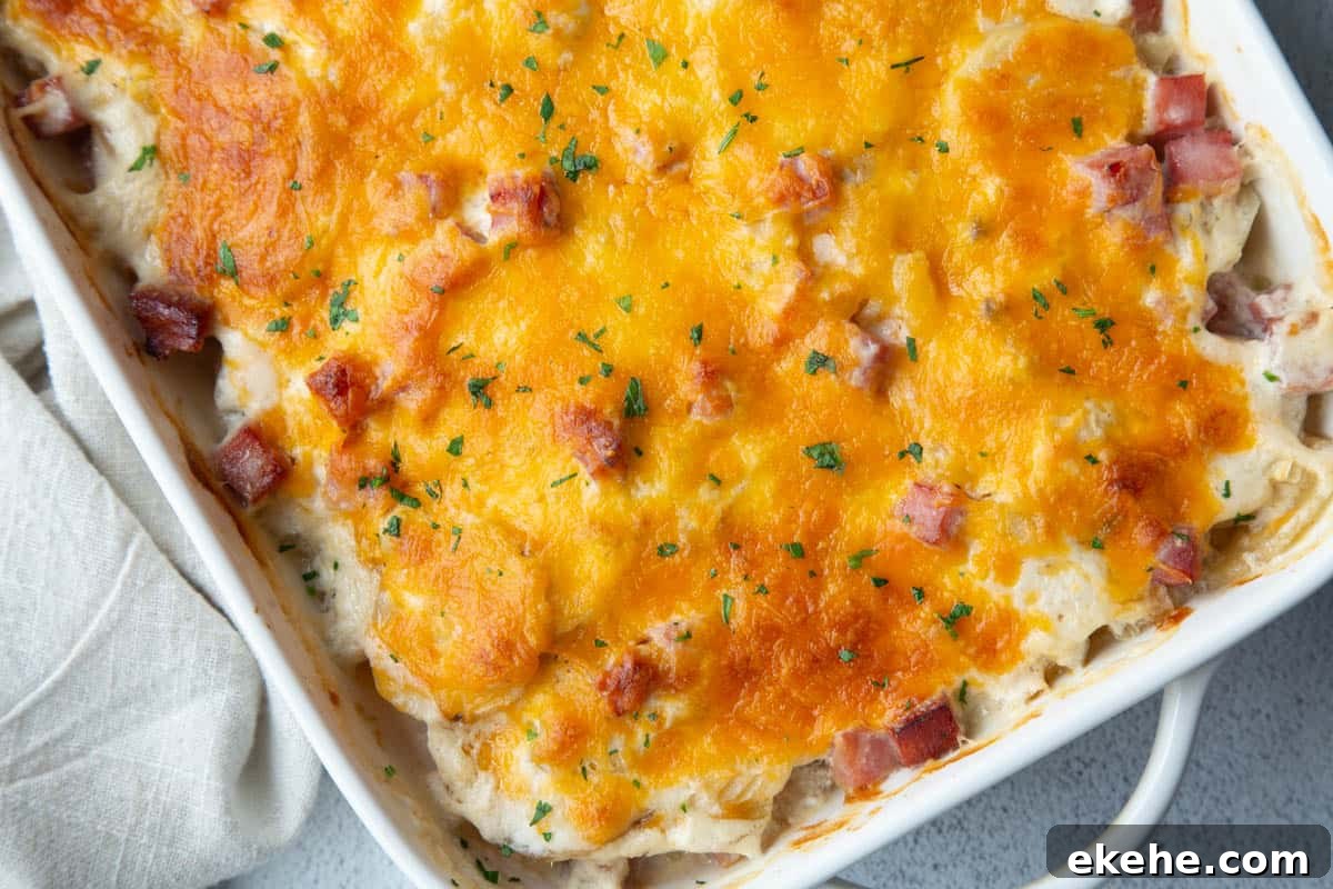 cheese topped scalloped potatoes in a white casserole dish. 