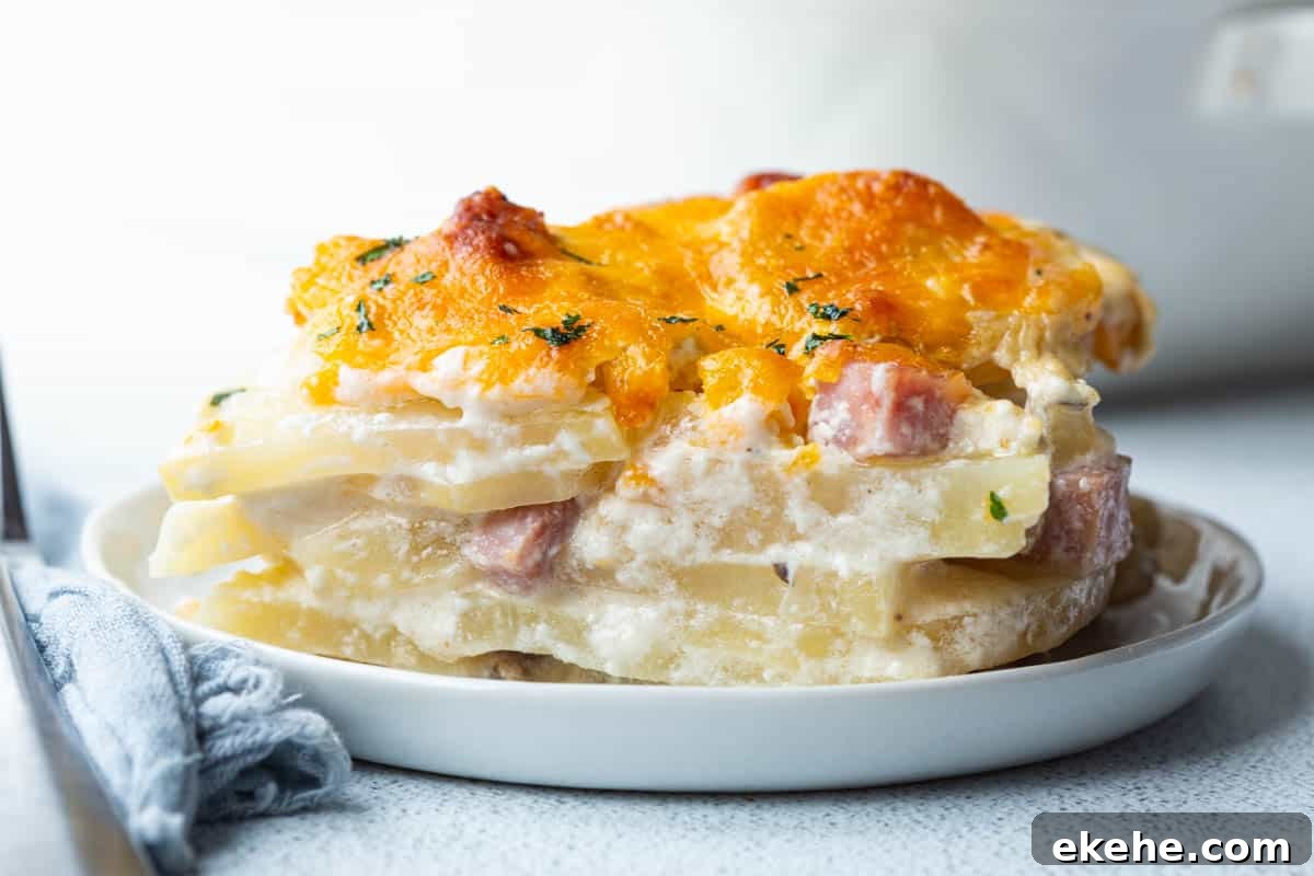 slice of scalloped potatoes and ham topped with melted cheese on a small white plate.