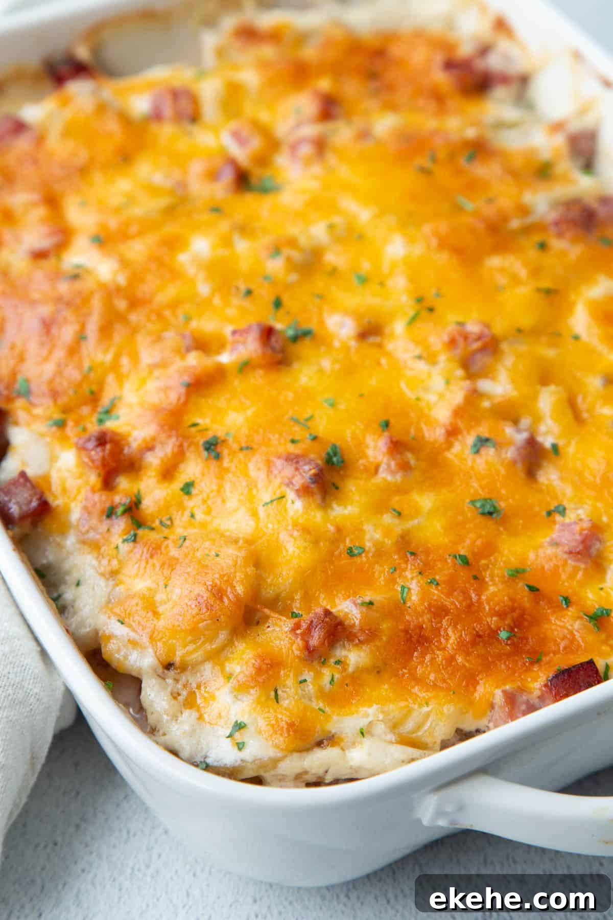 scalloped potatoes topped with cheese in a white casserole dish.