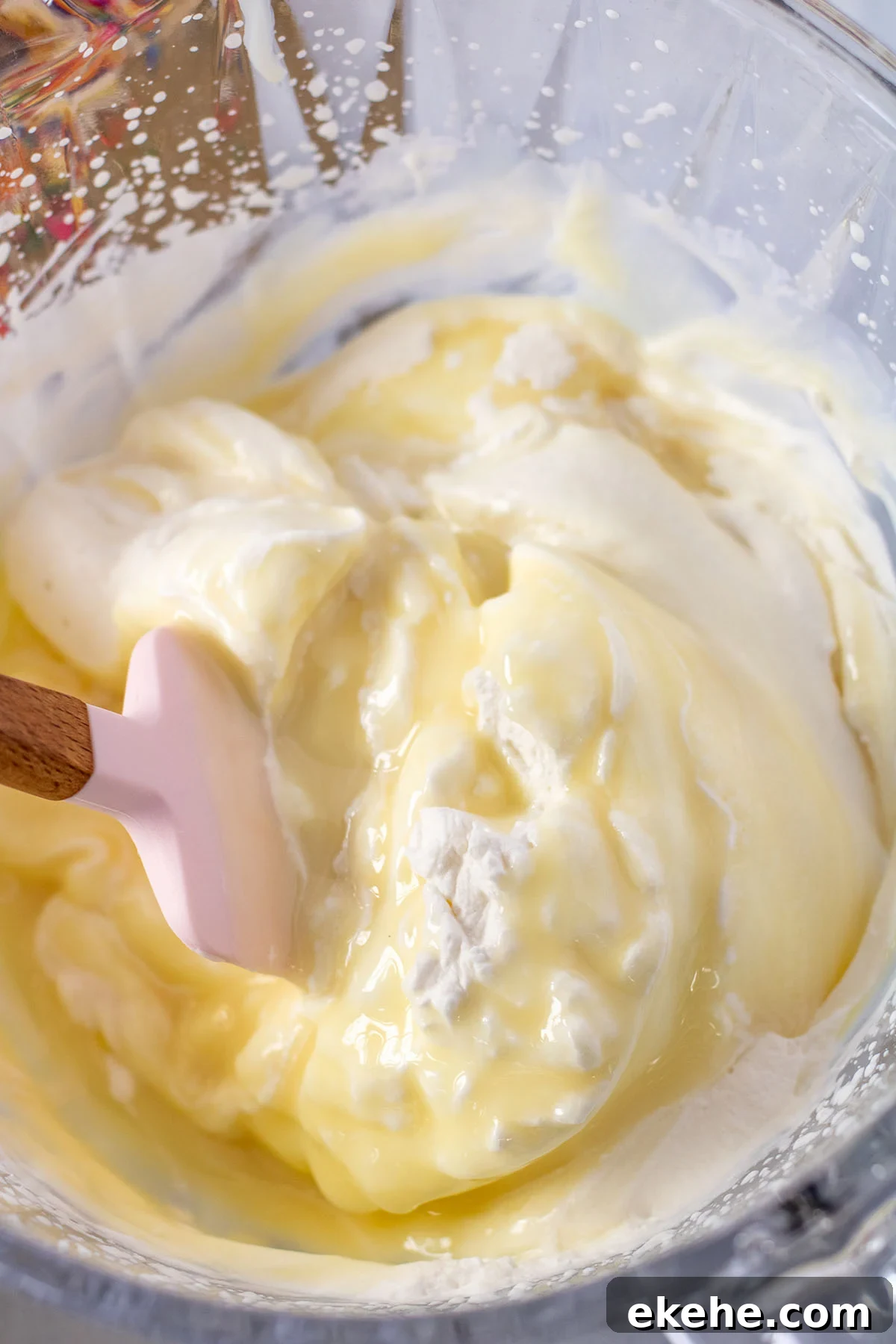 Sweetened condensed milk folded into whipped cream in the mixing bowl.