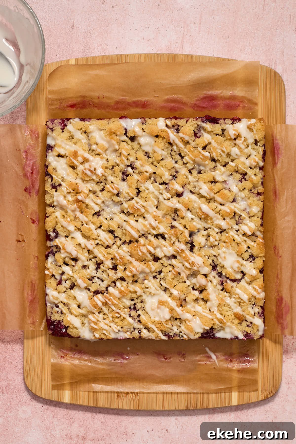 Bars on a wooden board with powdered sugar glaze drizzled over top.