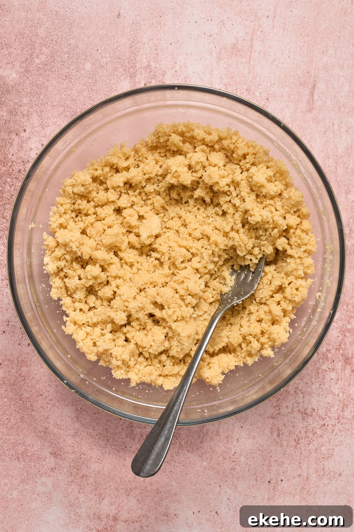 Crust and topping mixture in a glass bowl with a fork.