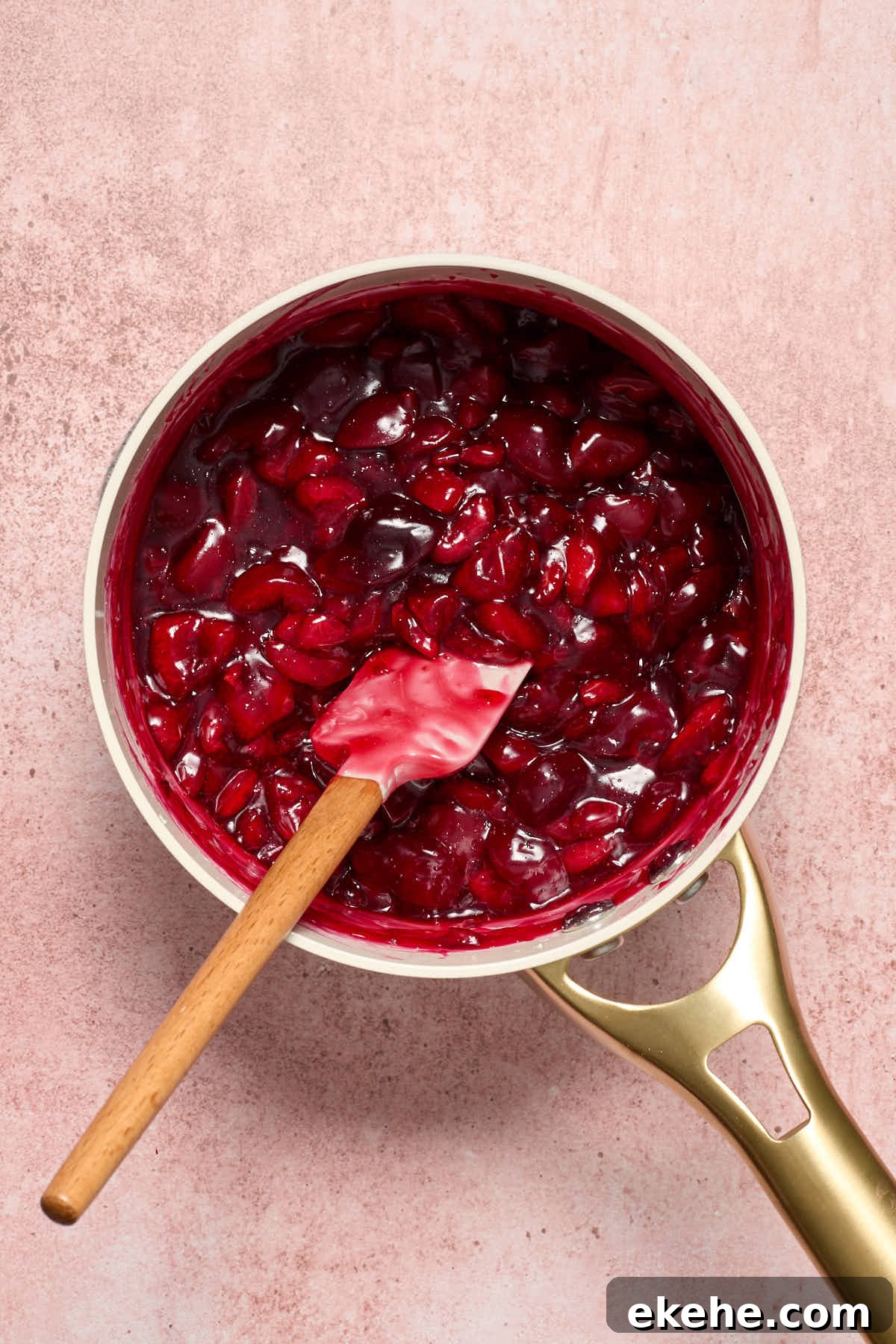 Cooked cherry pie filling in the saucepan with a spatula.
