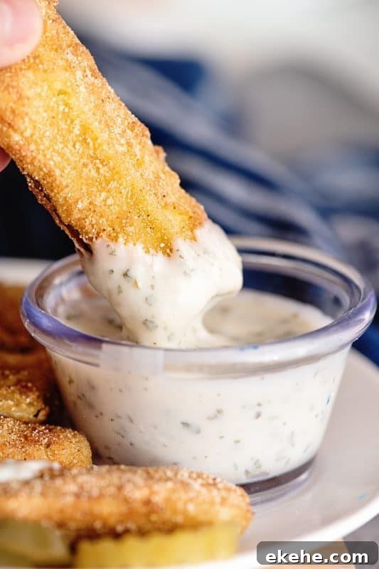 Dipping fried dill pickle in ranch dressing.