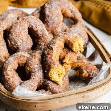 Basket of pumpkin spice soft pretzels. One pretzel is ripped in half to show the orange color inside.