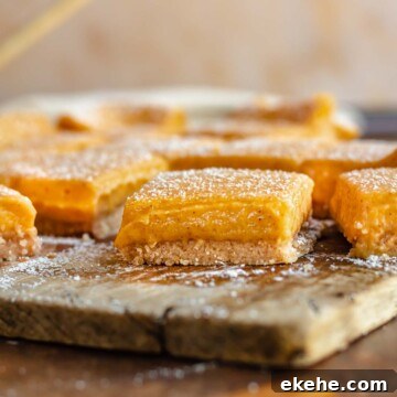 Pumpkin gooey bars on a cutting board cut apart and dusted with powdered sugar.