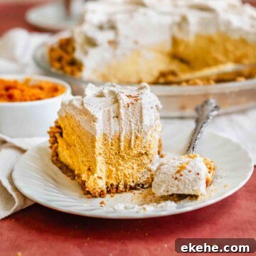A slice of pumpkin mousse pie on a plate. A fork holds a bite.