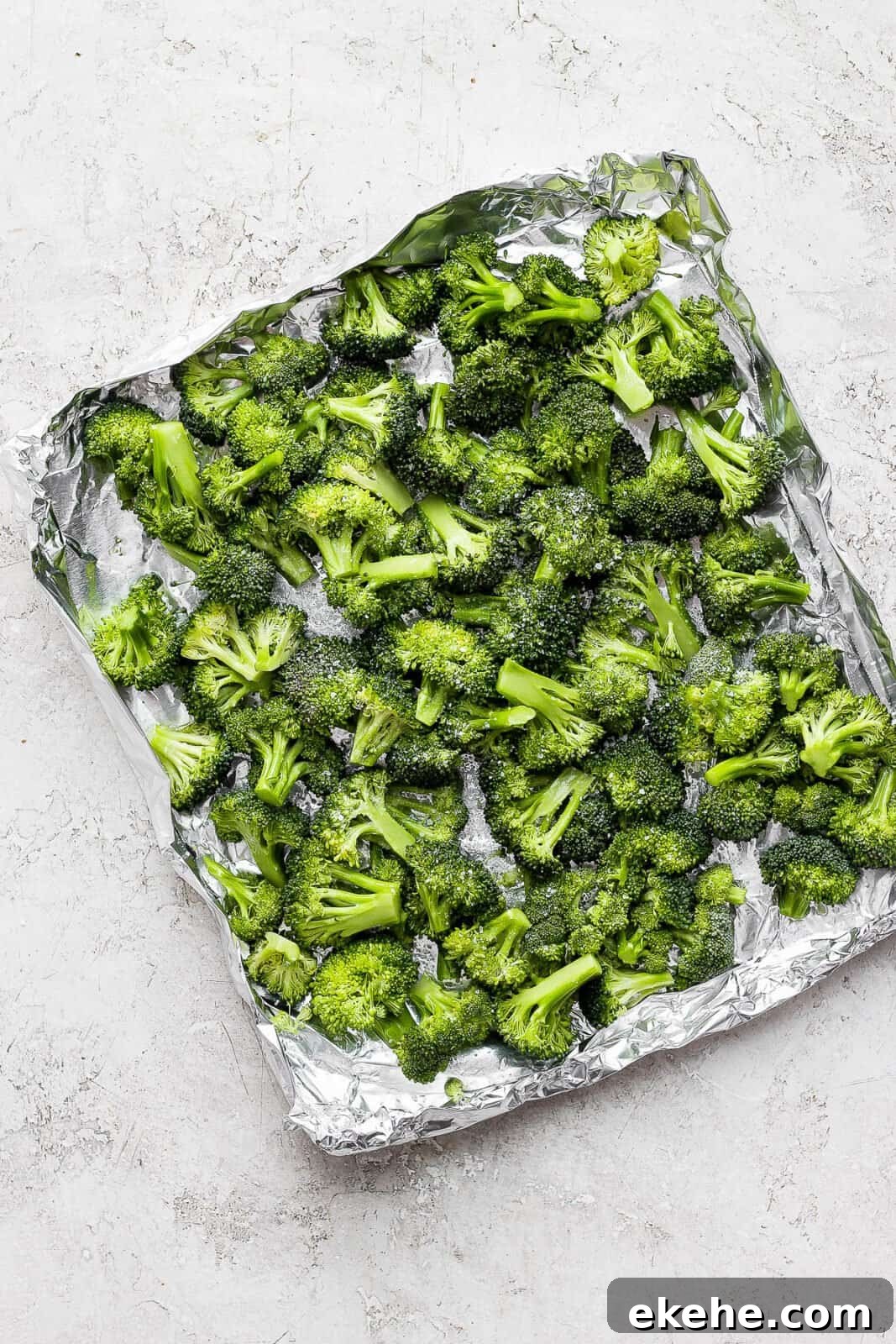 Broccoli florets in an aluminum foil boat after being coated in olive oil and salt sprinkled on top.