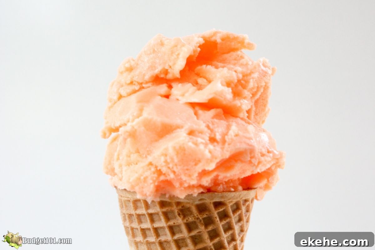 Creamy homemade orange Kool-Aid sherbet in a cone, perfect no-churn summer treat