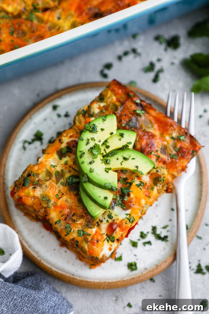 A slice of chorizo and egg breakfast casserole topped with sliced avocado and chopped cilantro