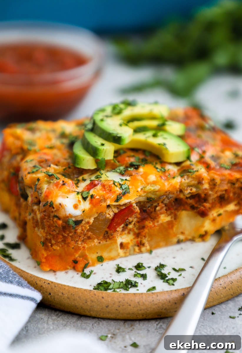 A close up photo of a chorizo and potato egg casserole topped with sliced avocado and chopped cilantro served with chunky salsa
