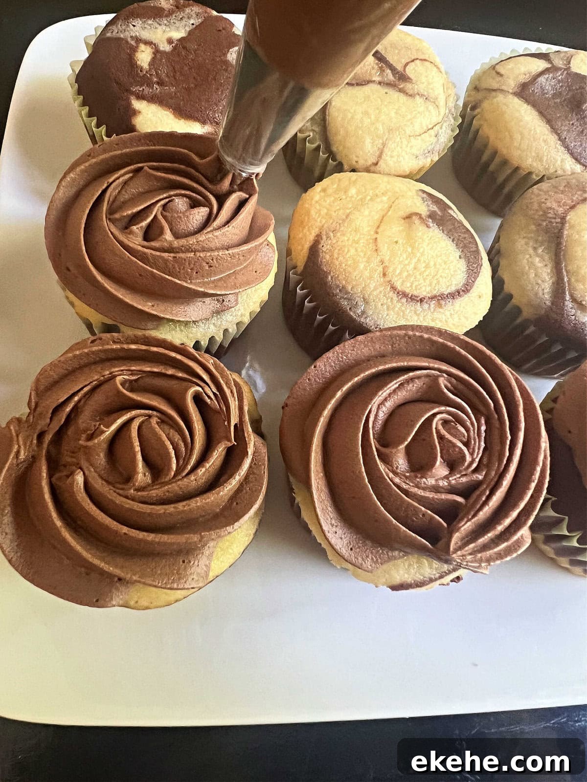 Piping rose swirls onto the marble cupcakes using a 2D piping tip.