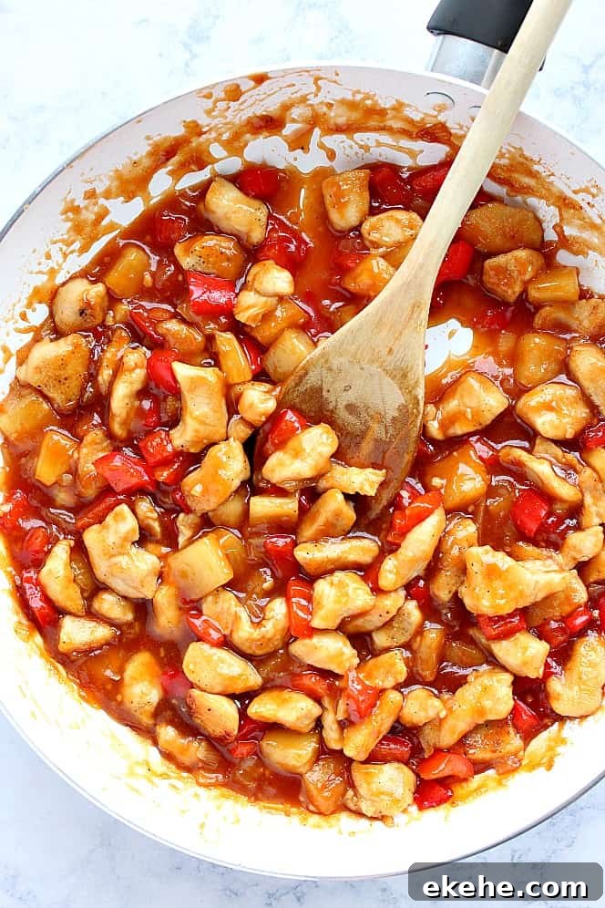Sweet and sour chicken cooking in a pan.