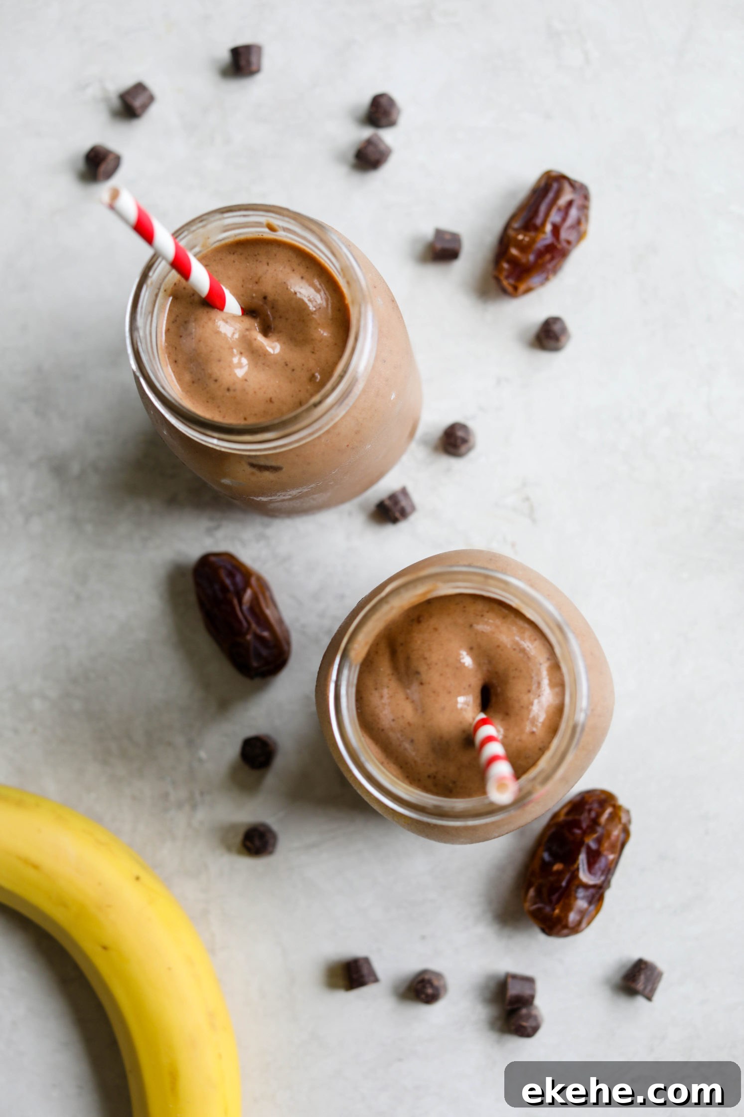 Healthy Vegan Chocolate Frosty served with red and white striped straws with dates, chocolate chips, and banana