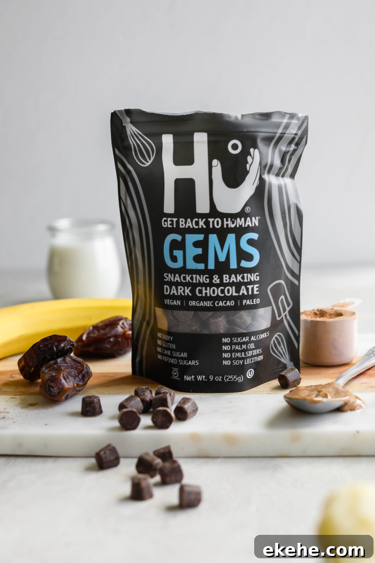 Hu Kitchen Chocolate Gems on board with chocolate chips, dates, almond butter, banana, and almond milk