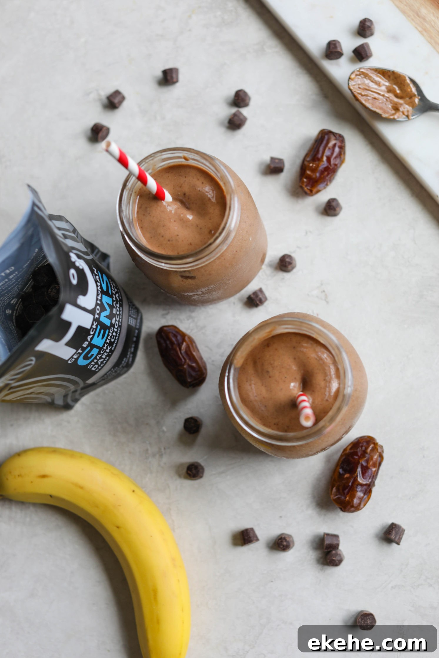 Healthy Vegan Chocolate Frosty served with red and white striped straws with dates, chocolate chips, and banana