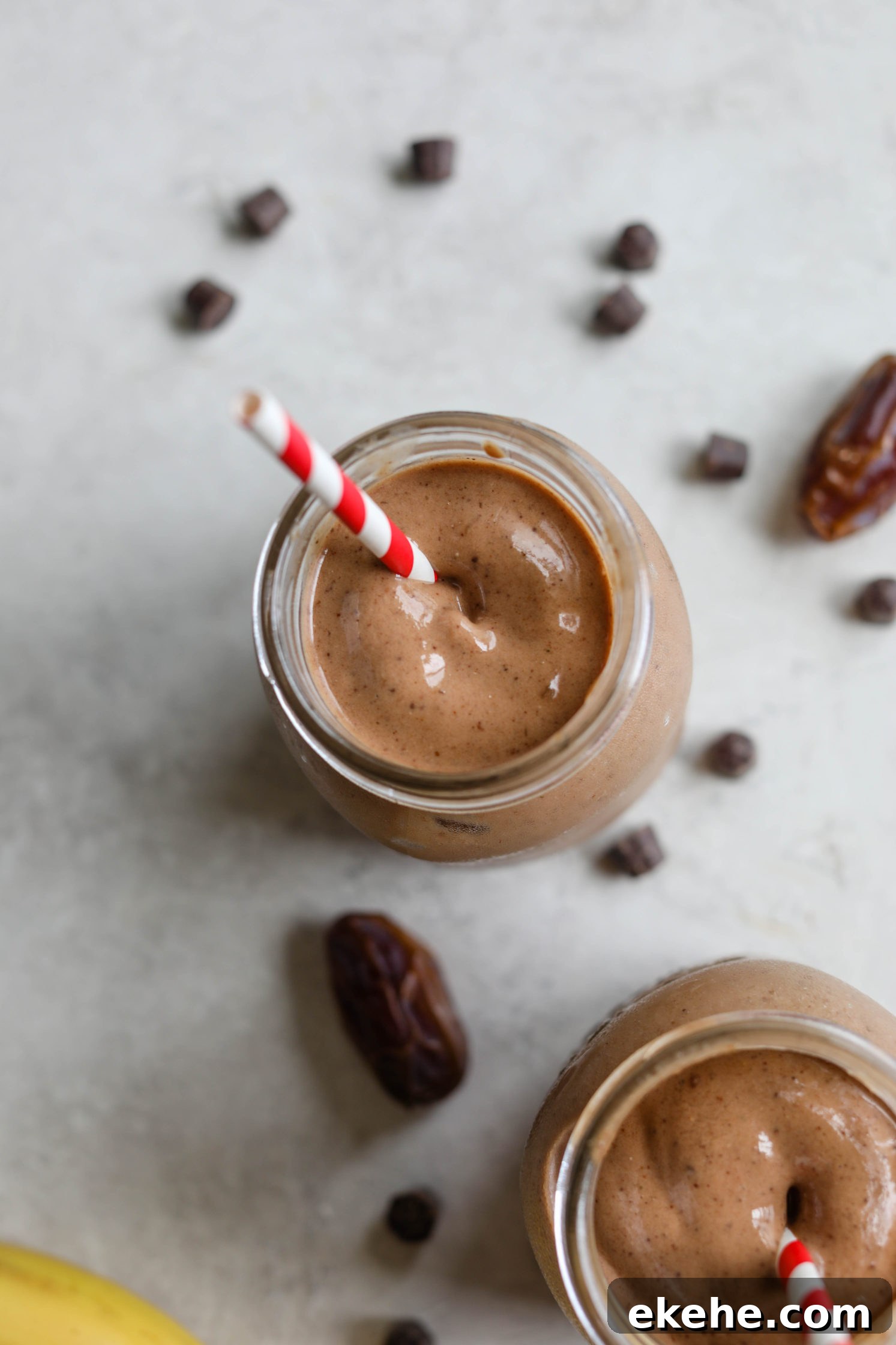Healthy Vegan Chocolate Frosty served with red and white striped straws with dates, chocolate chips, and banana