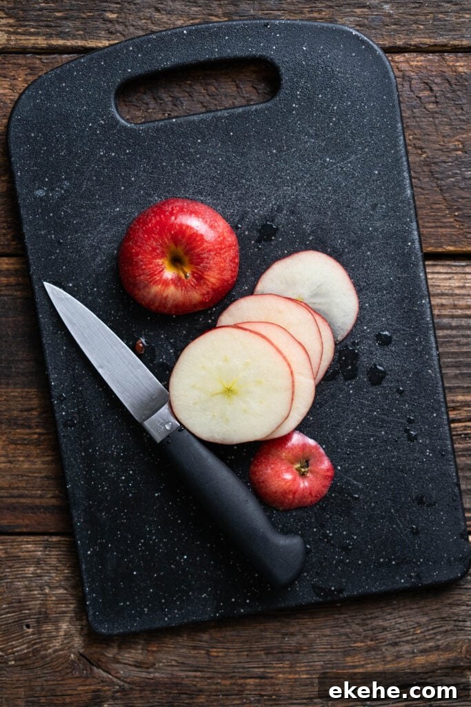 apple slices on a black cutting board with a knife