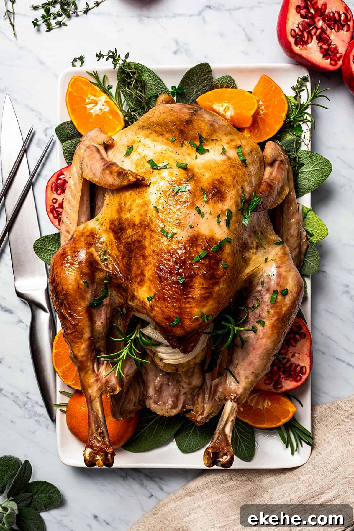 A whole roast turkey ready to carve, with carving utensils next to the platter.