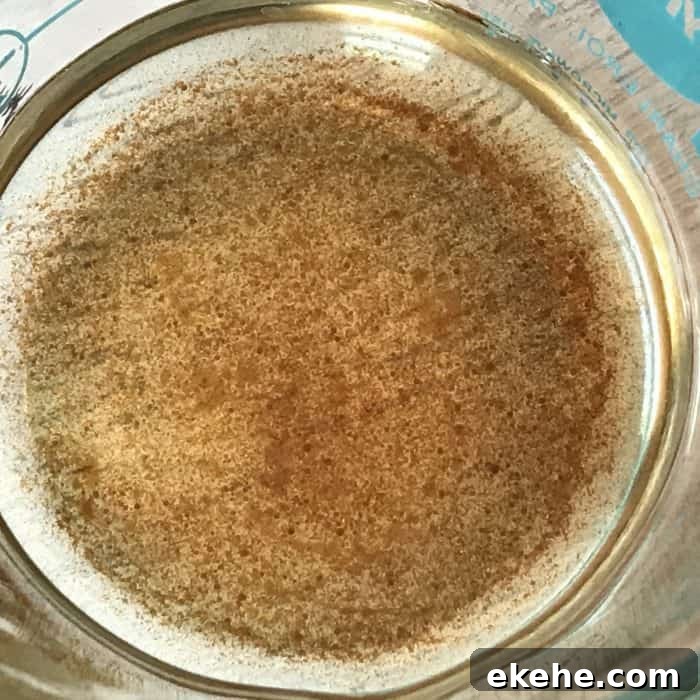 vanilla oleoresin and coconut oil stirred together in glass measuring cup