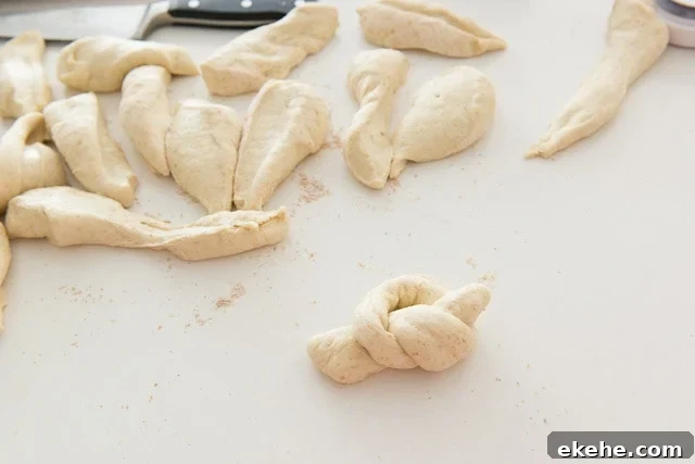 Buffalo Garlic Knot Recipe: Spicy, Cheesy Pull-Apart Rolls 11 Cut Pieces of Pizza Knot Dough on Countertop with One Tied Into Knot