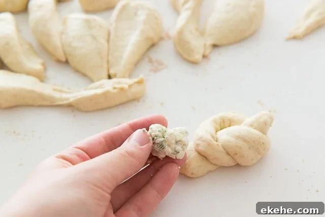Buffalo Garlic Knot Recipe: Spicy, Cheesy Pull-Apart Rolls 12 Hand Holding Clump of Blue Cheese To Be Stuffed Into Knot