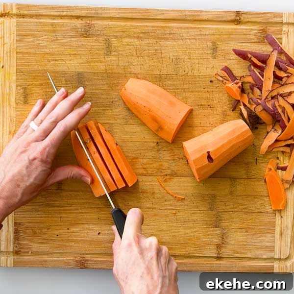 Hand slicing sweet potatoes on a cutting board for air fryer sweet potato fries.