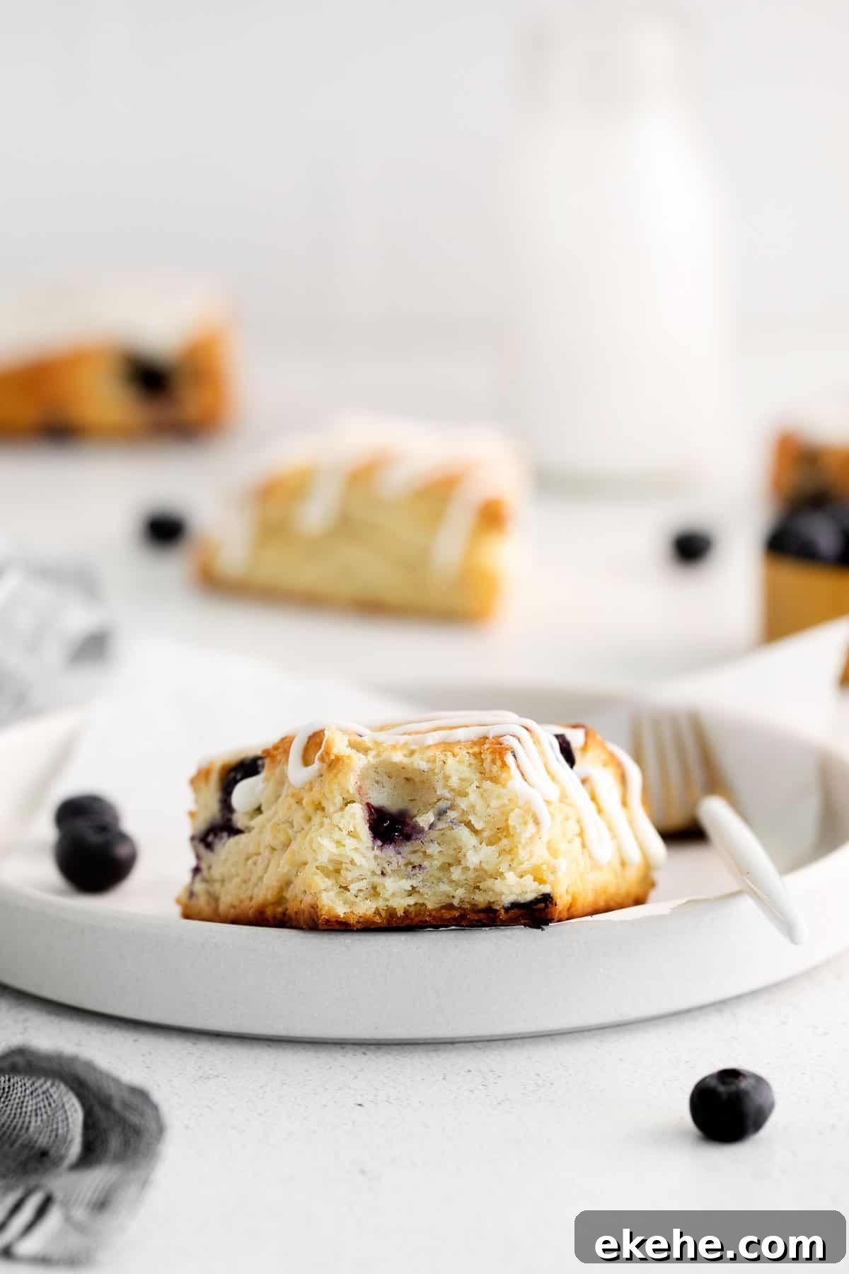 a blueberry scone with one bite missing on a plate.