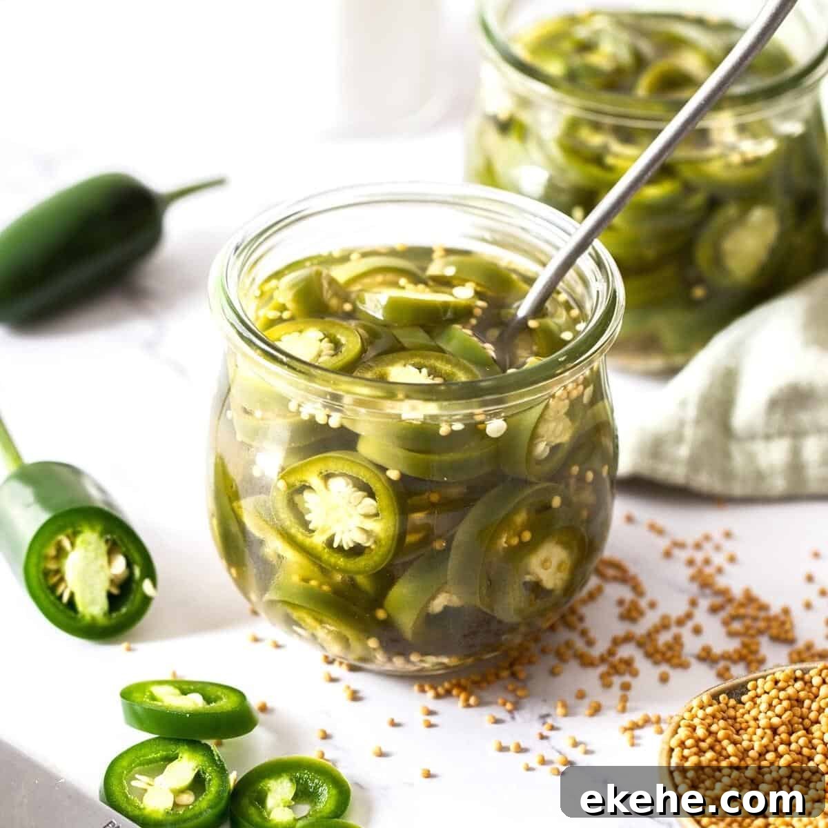 Jar of pickled jalapeños with a spoon sitting in jar, with some fresh jalapeños around the edge.