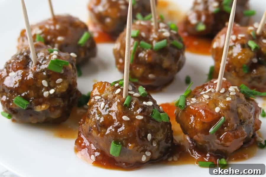 sweet & spicy meatball appetizer garnished with chives and sesame seeds 