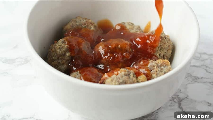 sweet & spicy apricot glaze being poured over the best baked meatballs