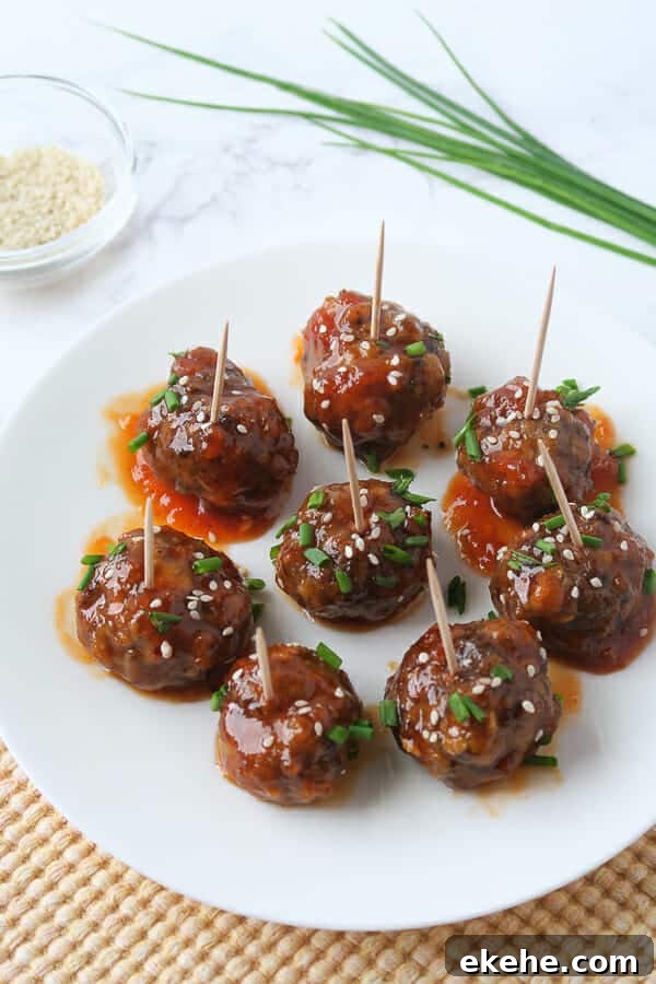  sweet & spicy meatball appetizer garnished with chives and sesame seeds 