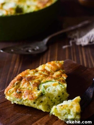 Angled view of zucchini pie on a brown cutting board with a fork cut into a slice.
