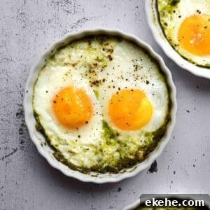 Overhead view of baked eggs in ramekins with pesto,