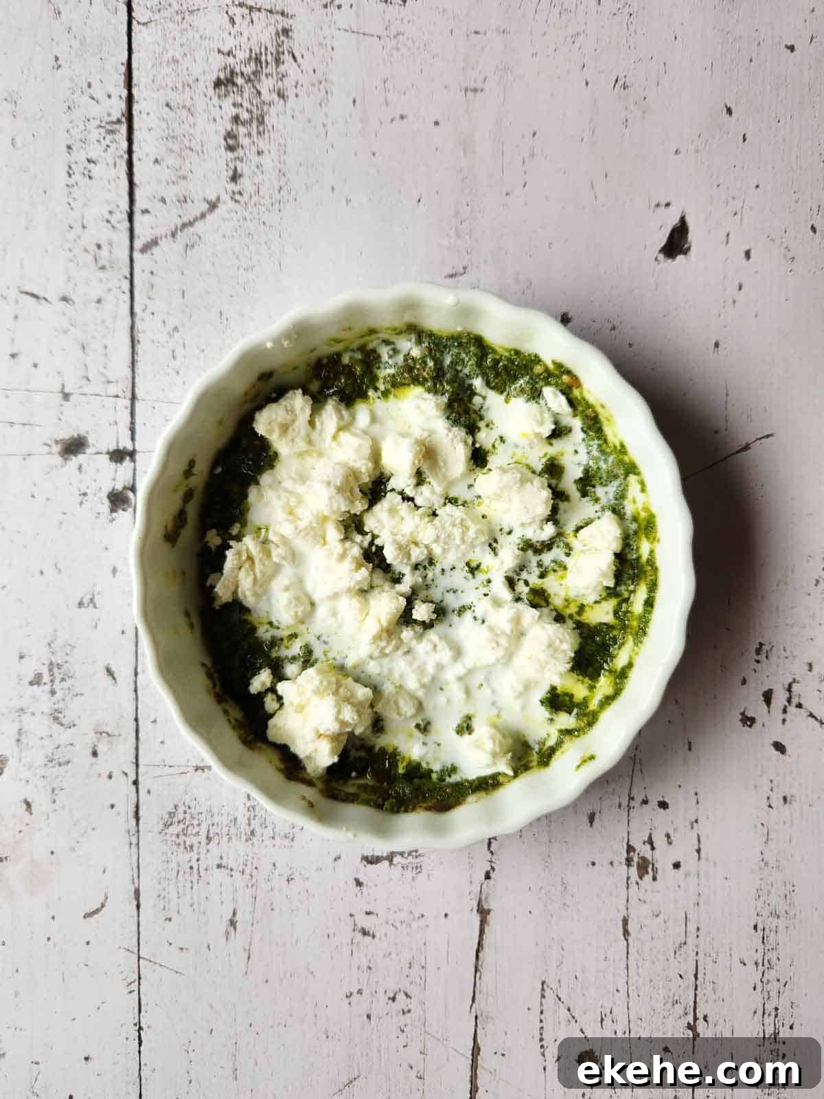 Pesto sauce, feta and cream in a white ramekin.